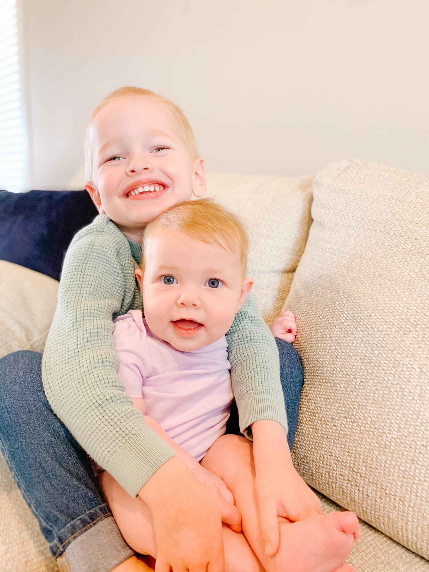 toddler and baby brother and sister hugging and smiling